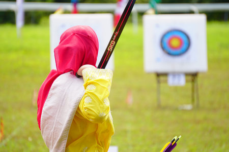 Archery wearing traditional dress target ring and out of focus archer with a bow in the foreground...