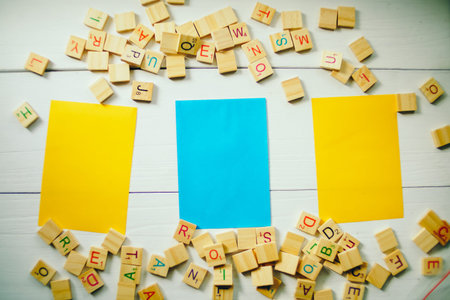 Colorful Sticky note on a wooden background with wooden alphabet. 