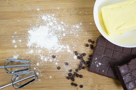 Butter and chocolate bar and chocolate chips on a wooden background. Ingredients preparation in...