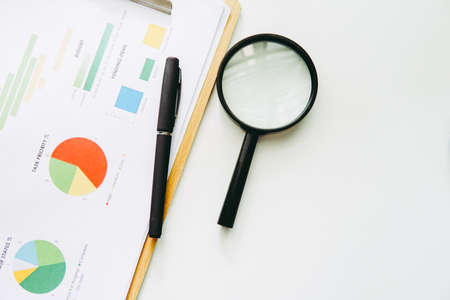 Magnifying glass and pen over graph on table. Financial concept. Businessの写真素材