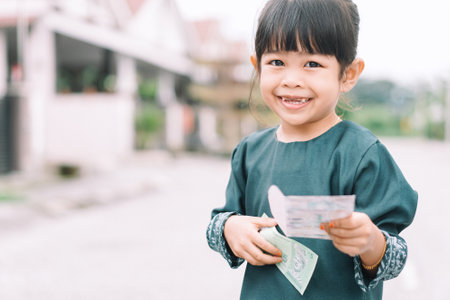 Cute Malay girls Malay traditional cloth showing his happy reaction after received money pocket during Eid Fitri or Hari Raya celebrationの写真素材