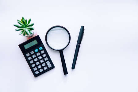 Business financial concept, black pen with magnifying glass and calculator over white background. copy space conceptの写真素材