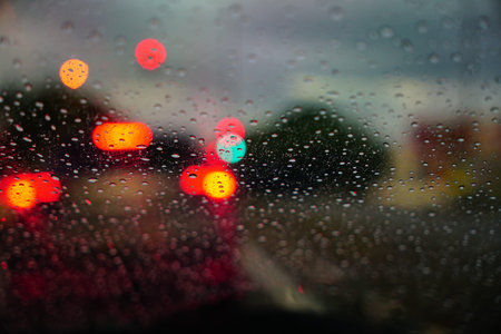 Traffic light bokeh with rain drops. Reflections of raindrops on glass on car window. Raindrops...