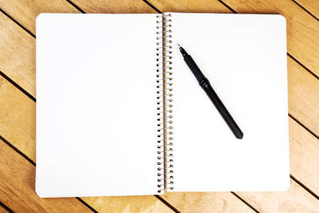 Blank notepad with blank pen on wooden tableの写真素材