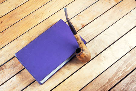 Smoking pipe and old book on the wooden tableの写真素材