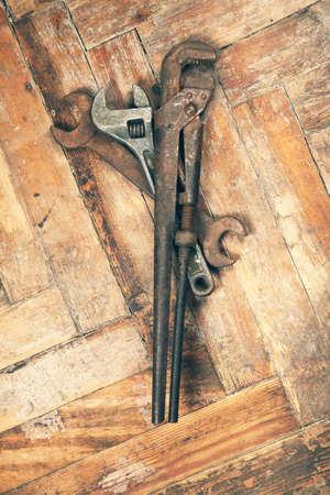 Set of old adjustable spanner, pipe wrench and open-end wrench on wooden floorの写真素材