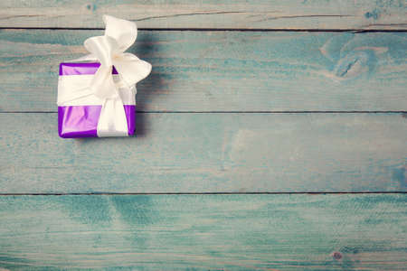 Violet gift box with bow on  wooden backgroundの写真素材