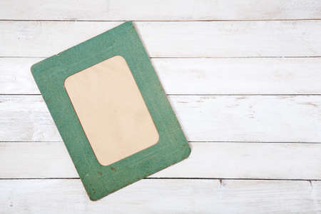 Retro green photo frame on white wooden background. Top viewの写真素材