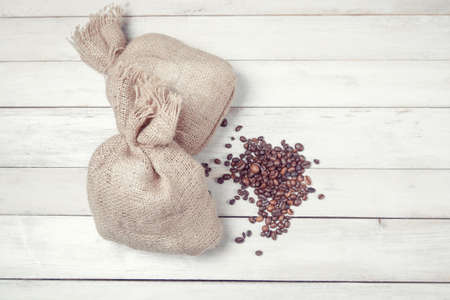 Coffee beans with burlap sacks on white wooden tableの写真素材