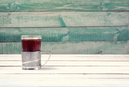 Cup of tea in vintage glass-holder on white wooden backgroundの写真素材