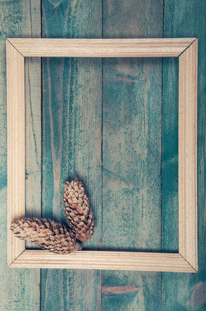 Photo frame with two pine cones on old wooden background