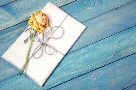 One dried yellow rose with blank photo frame on old blue wooden background
