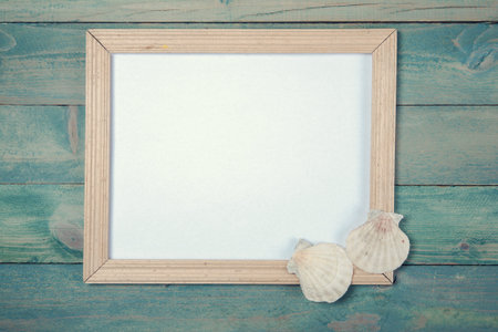 Blank photo frame with sea shells on wooden background