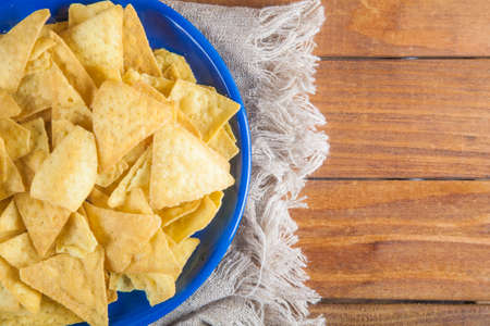 Nachos corn chips in blue plate on sackcloth on wooden table with copy space. Top viewの写真素材