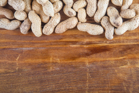 Not peeled peanutson wooden background with copy space. Top view