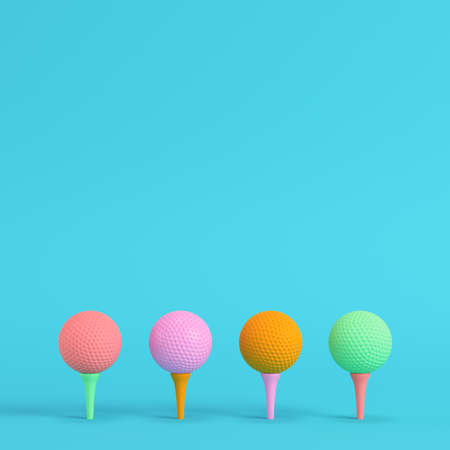 Four colorful golf balls with tee on bright blue background in pastel colors. Minimalism concept. 3d renderの写真素材
