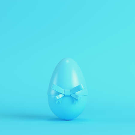 Easter egg with bow on bright blue background in pastel colors. Minimalism concept. 3d renderの写真素材