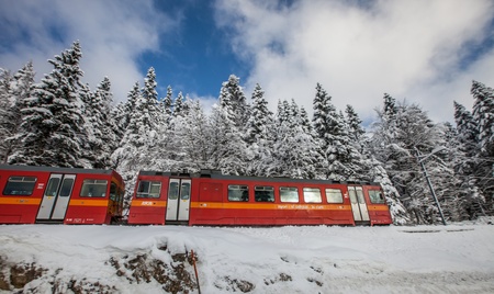 30th November 2012. La Givrine, St Cergue, Switzerland.  An electric red train traveling thorugh a Swiss winter landscape in Jura mountain.のeditorial素材