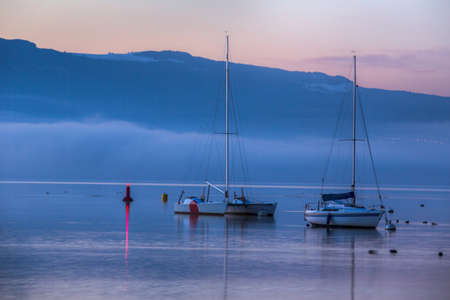 Sunrise and sailboats at a small bay in lake Geneva, Switzerlandの写真素材