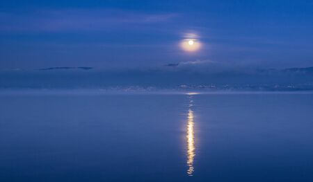 Full moon over Jura mountain range and Lake Geneva in a winter dawnの写真素材