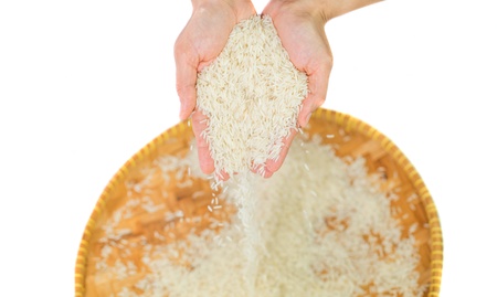 Hand releasing rice grain into a wicker trayの写真素材