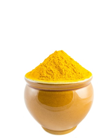 Turmeric powder in a ceramic container over white backgroundの写真素材