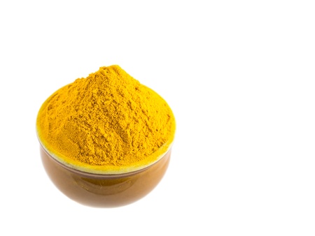 Turmeric powder in a ceramic container over white backgroundの写真素材