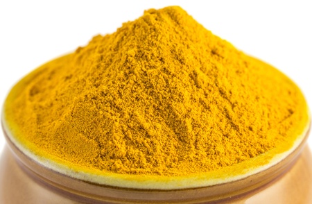 Turmeric powder in a ceramic container over white backgroundの写真素材