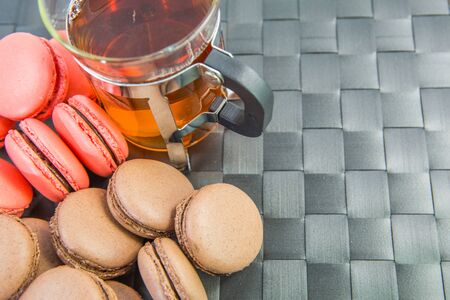 A group of chocolate and pink French macarons and a mug of teaの写真素材