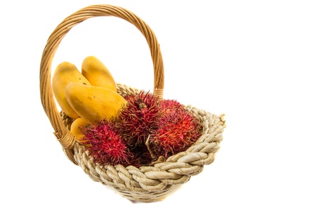 Rambutan and mango fruits in a basket over white backgroundの写真素材
