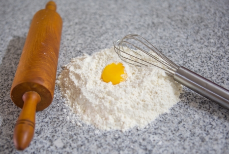 Flour, egg beater and rolling pin on a granite counter surface の写真素材