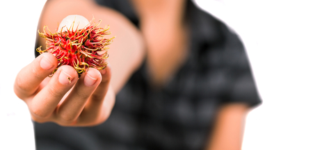 A Malay Asian girl offering a rambutan fruitの写真素材