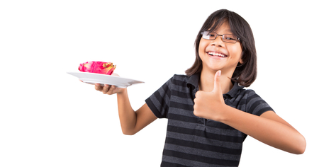 An Asian Malay little girl eating a dragon fruit の写真素材