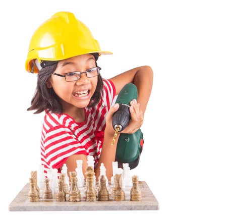 Concept image of little girl destroying a stone chess set with a power drillの写真素材