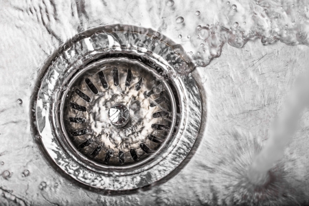 Water flowing down the hole in a kitchen sinkの写真素材