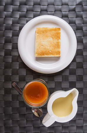 A glass of tea, bread toast and condensed milk の写真素材