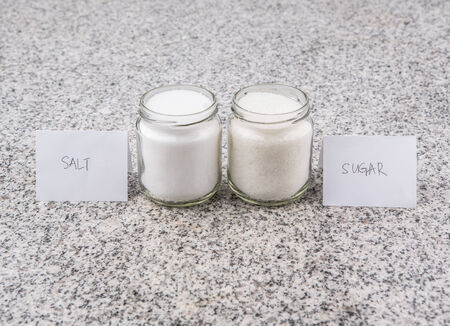 Salt and sugar in a glass bottle on granite surface の写真素材
