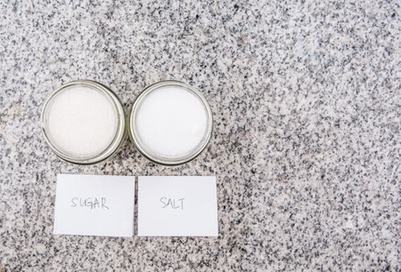 Salt and sugar in a glass bottle on granite surface 