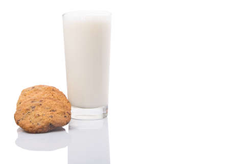 A glass of milk and home made cookies over white backgroundの写真素材