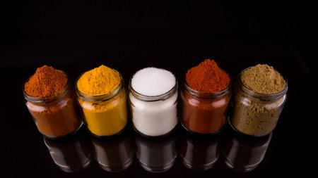 Mix powdered spices in glass container over black background