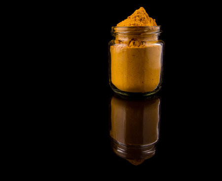 Powdered tumeric spices over black backgroundの写真素材