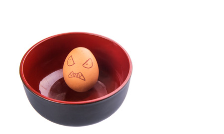Chicken egg with drawn face expression in a bowlの写真素材