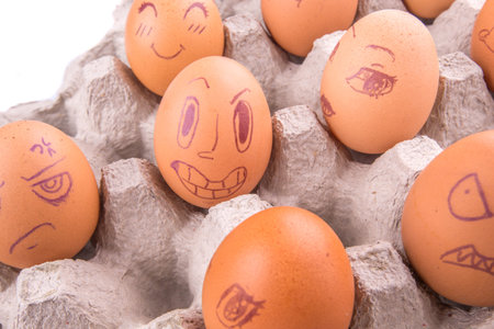 Chicken eggs with drawn face expression in an egg carton