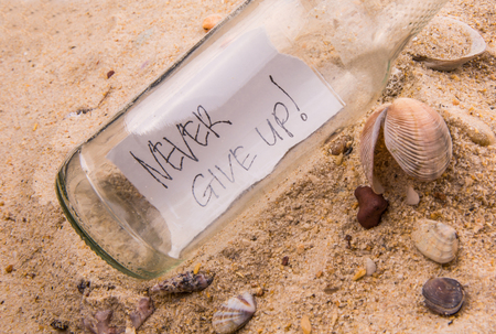 Concept image of a message NEVER GIVE UP in a bottleの写真素材
