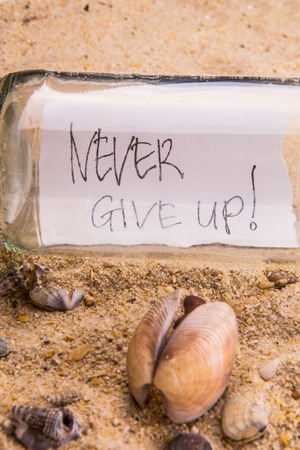 Concept image of a message NEVER GIVE UP in a bottleの写真素材