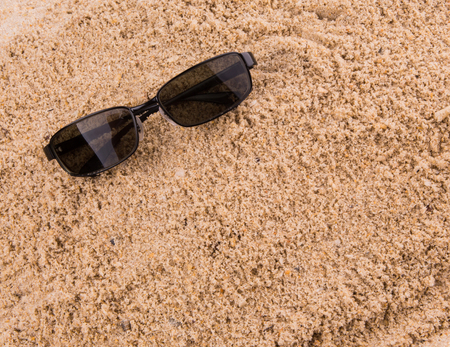 Pair of sunglasses on beach sandの写真素材