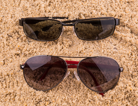 Pair of sunglasses on beach sandの写真素材