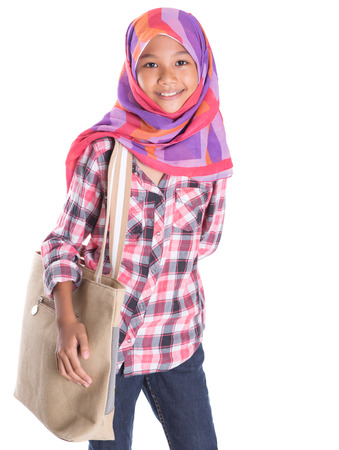 Young Muslim school girl with a large handbag over white backgroundの写真素材