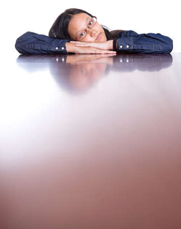Young Asian Malay girl with her face reflection on a wooden table surface の写真素材