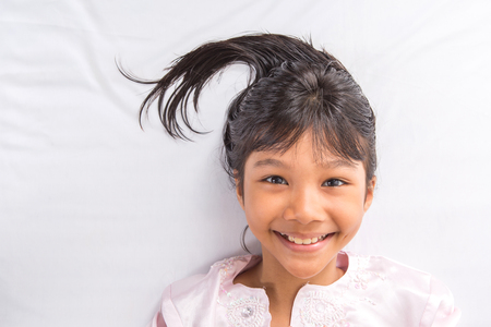 Playful young Asian girl on her bedの写真素材